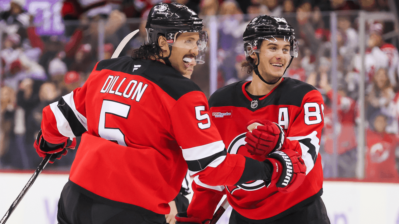 NEWARK, NJ - NOVEMBER 30: New Jersey Devils center Jack Hughes (86) and New Jersey Devils defenseman Brenden Dillon (5) celebrate after New Jersey Devils left wing Jesper Bratt (63) (not pictured) scores a goal during a NHL game between the Washington Capitals and New Jersey Devils at Prudential Center on November 30, 2024 in Newark, New Jersey.